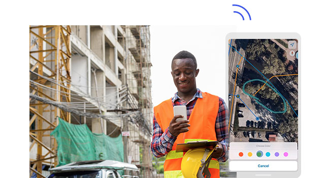 Fieldworker holding a mobile phone, hard hat, and a clipboard at a construction site. Phone screenshot with the area circled in green.