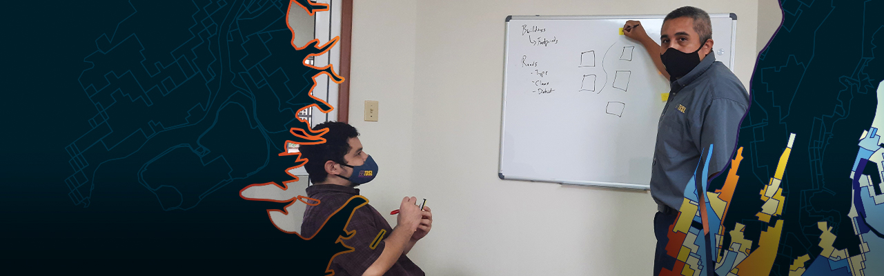 Two professionals in an office are collaborating over a planning wall covered in small notes